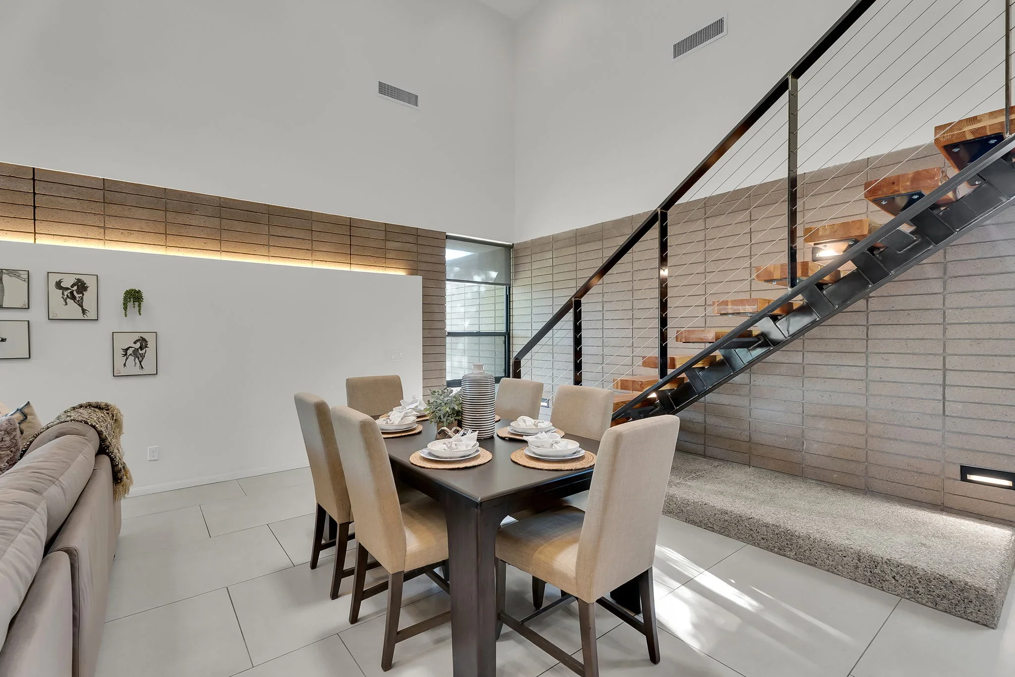 Modern dining room with shiplap walls, floating staircase, and open-concept layout