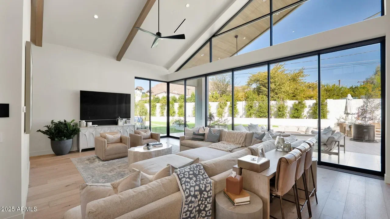 Modern living room with floor-to-ceiling glass doors, wood beams, and open layout