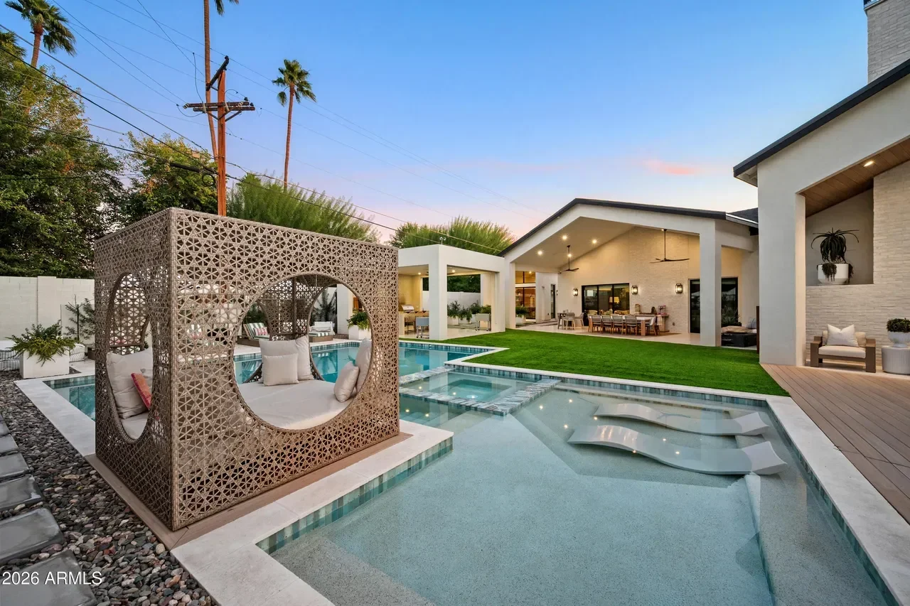 Resort-style backyard with pool, spa, geometric shade structure, and modern home exterior
