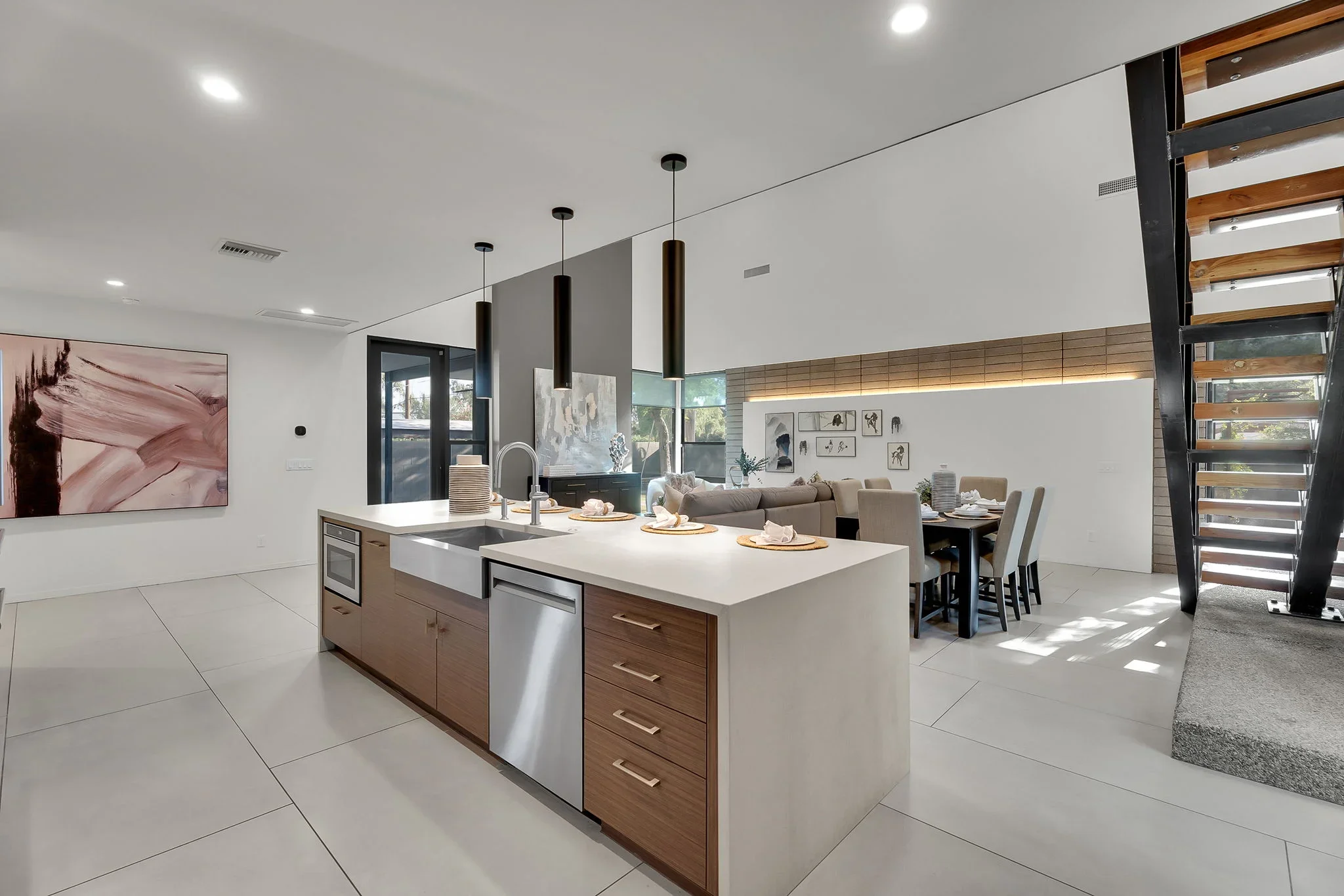 Modern kitchen with white quartz island, wood cabinetry, stainless steel appliances, and open living space