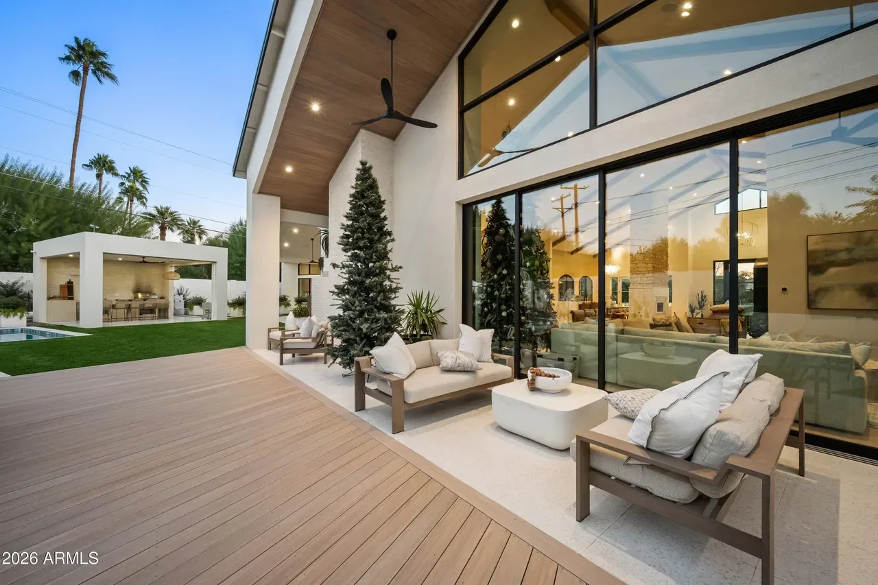 Modern patio with composite decking, frameless glass doors, wood ceiling, and outdoor furniture