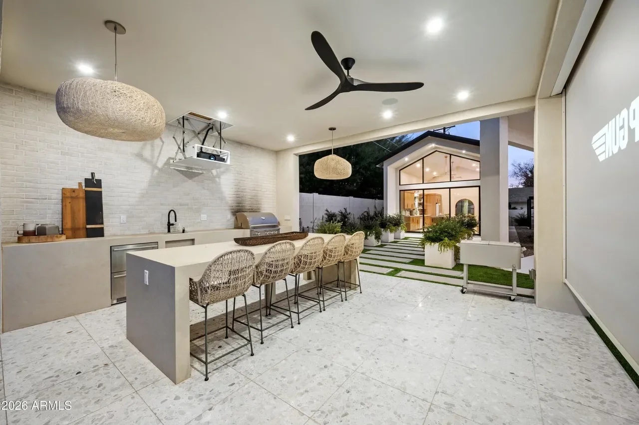 Modern outdoor kitchen with island, quartz counters, stainless appliances, and concrete patio