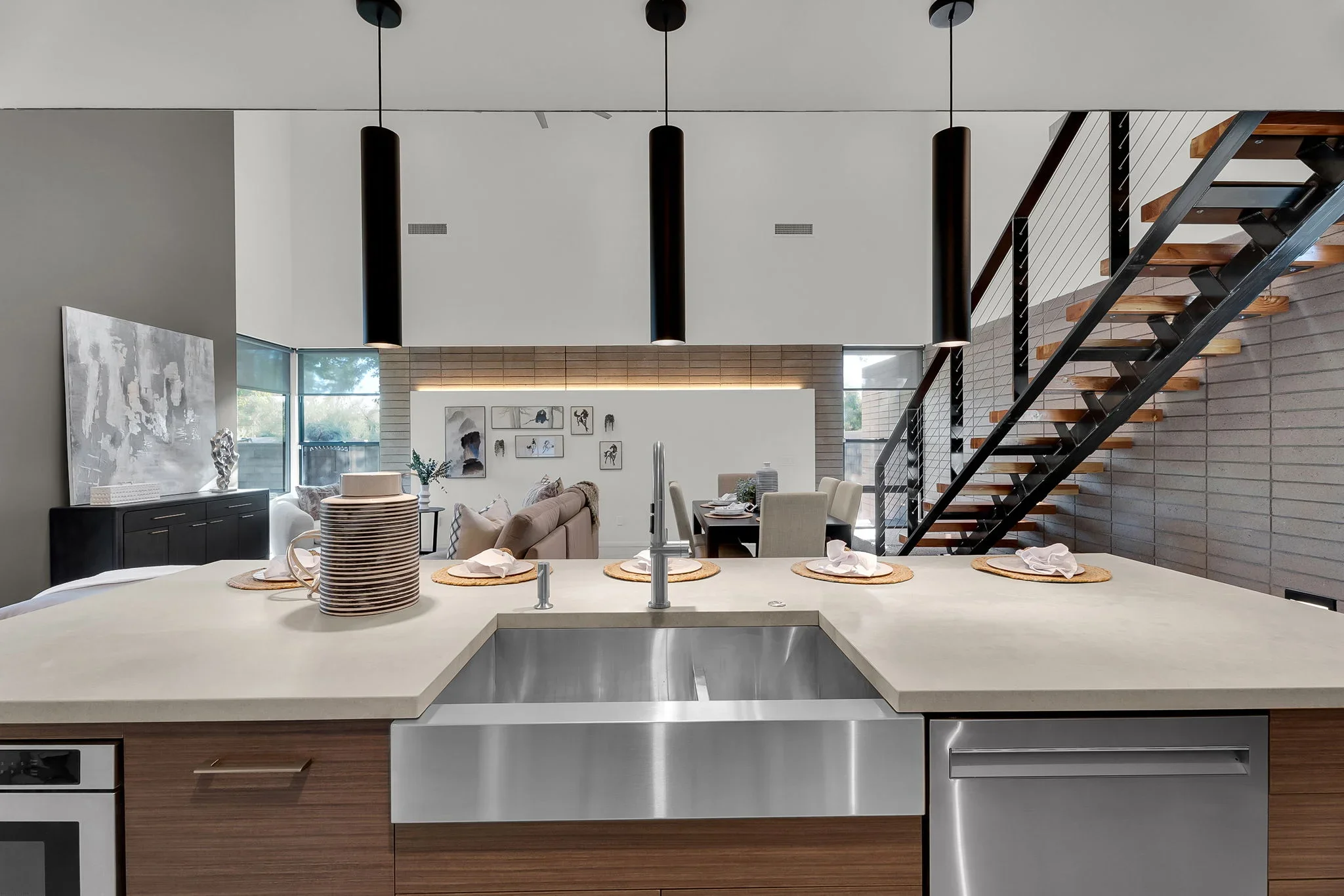 Modern kitchen with stainless steel farmhouse sink, quartz countertops, wood cabinetry, and open living space