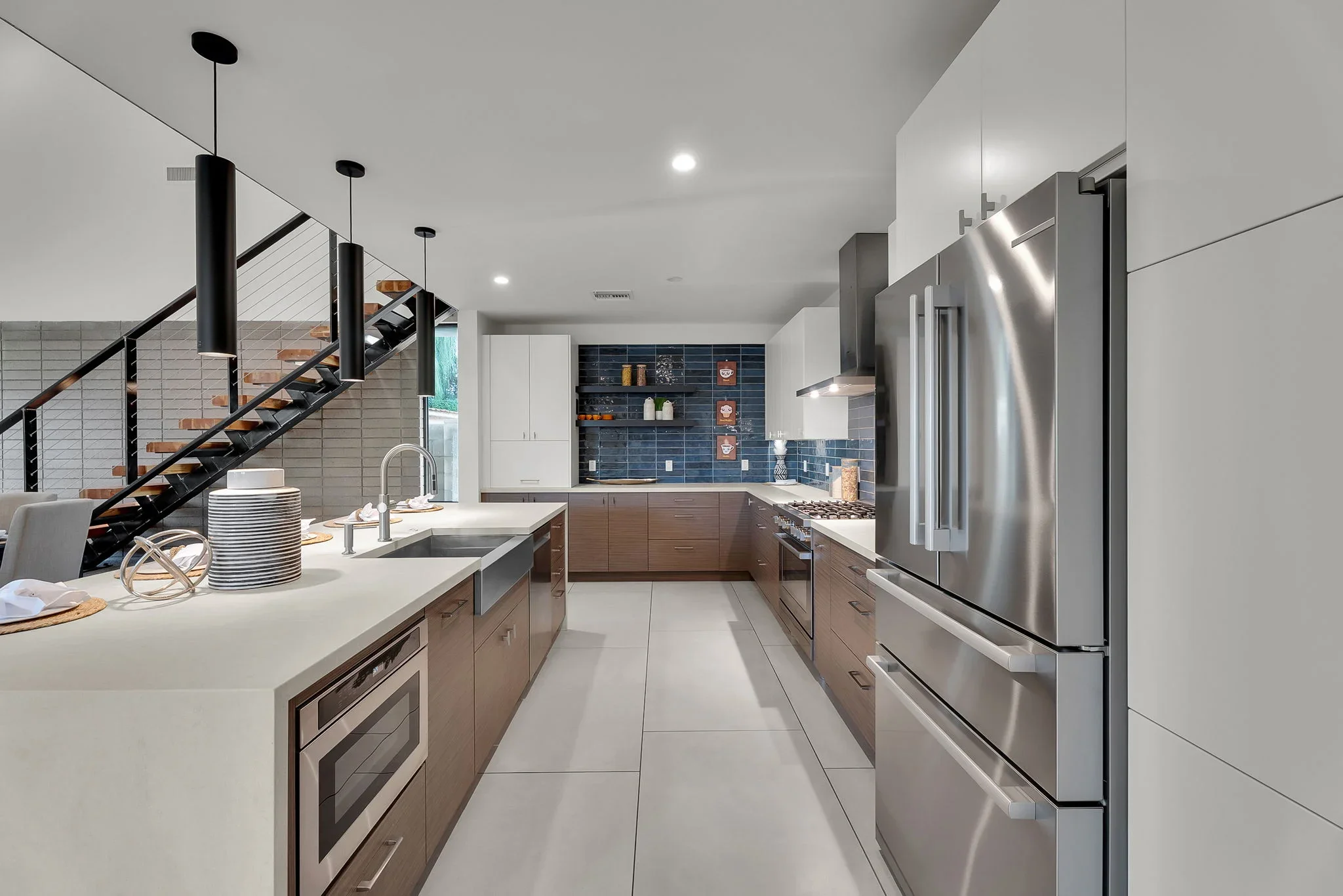 Modern kitchen with wood cabinetry, quartz counters, stainless appliances, blue tile backsplash