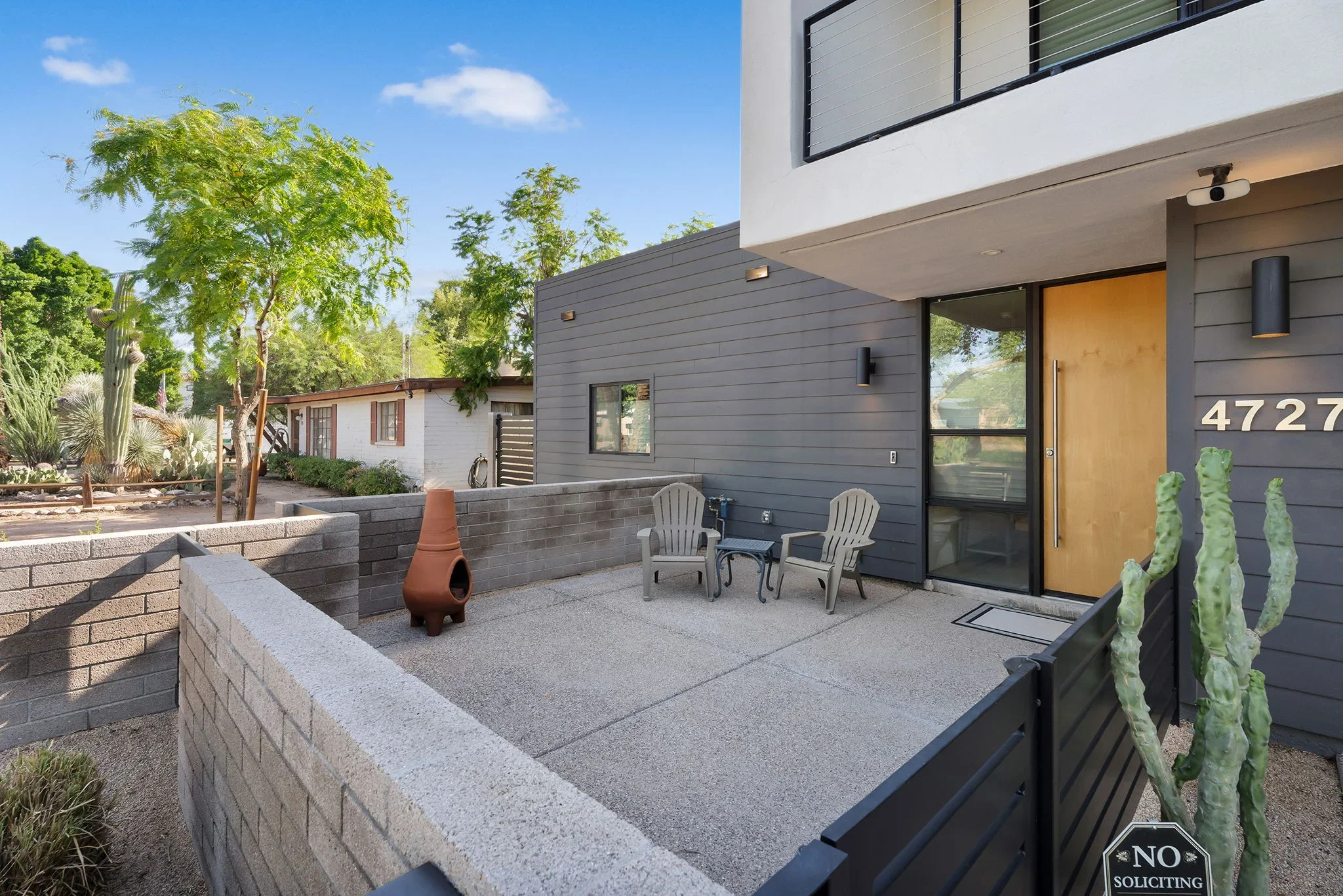 Modern home addition with gray fiber cement siding, concrete patio, and retaining walls