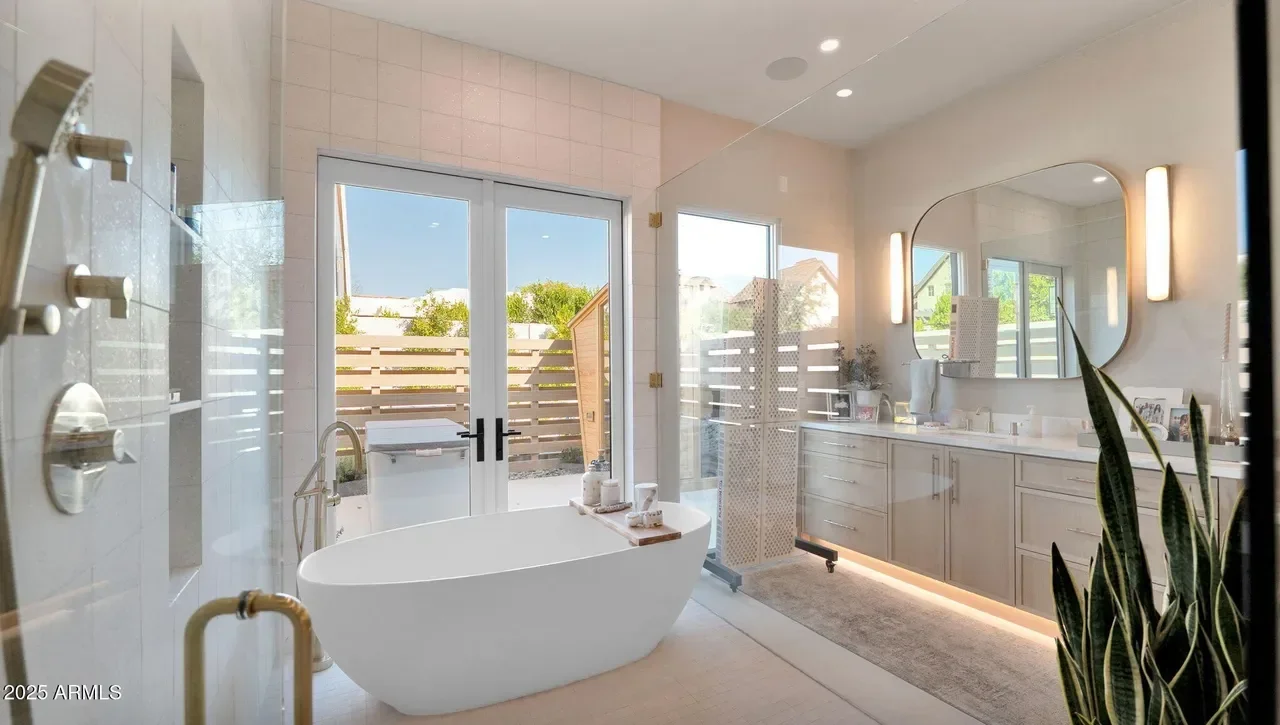 Modern bathroom with white freestanding tub, glass shower, dual vanity, and outdoor deck access